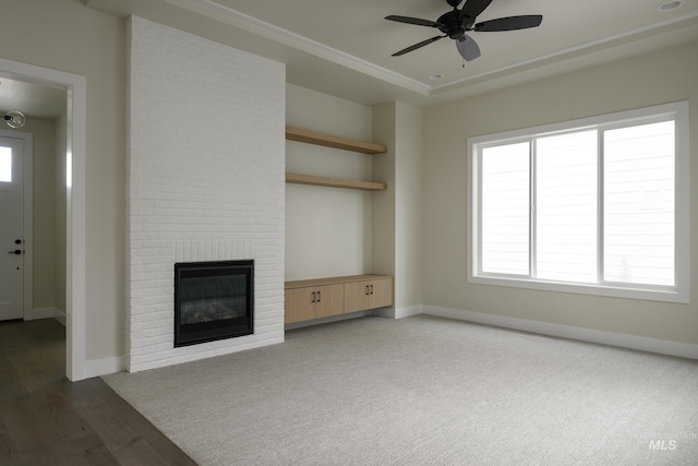 unfurnished living room with ceiling fan, a fireplace, baseboards, and wood finished floors