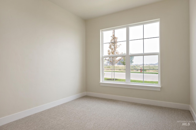 spare room with light colored carpet and baseboards