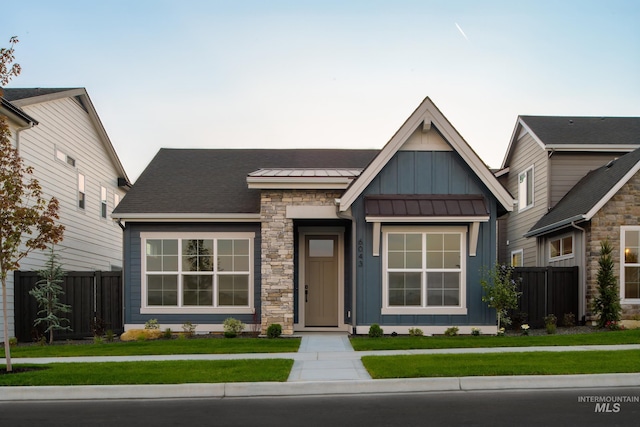 view of front of property with board and batten siding, a front yard, and fence