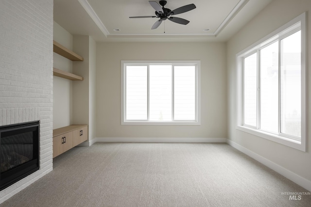 unfurnished living room featuring a raised ceiling, a fireplace, and baseboards