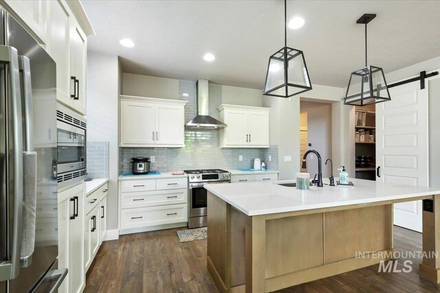 3303 S Island Fox Ave, Eagle, ID 83616 - kitchen with stainless steel appliances, wall chimney range hood, backsplash, an island with sink, and light countertops