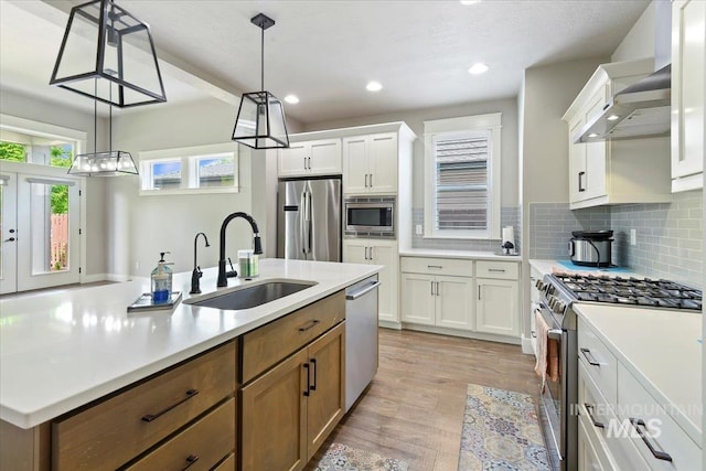 3303 S Island Fox Ave, Eagle, ID 83616 - kitchen with stainless steel appliances, a sink, ventilation hood, light wood-type flooring, and a kitchen island with sink