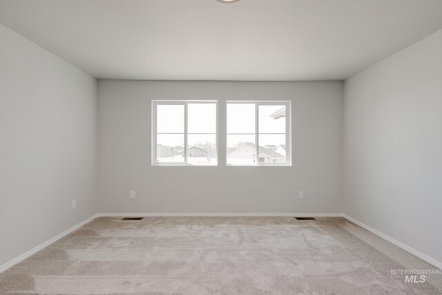 empty room featuring visible vents, baseboards, and light carpet