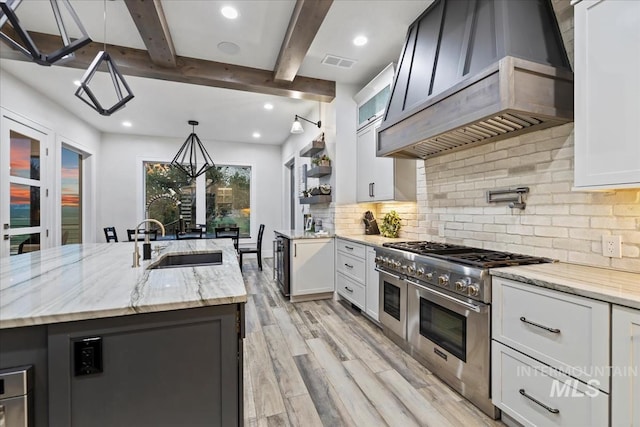 kitchen with white cabinetry, range with two ovens, sink, and hanging light fixtures