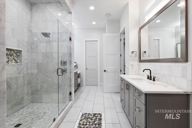 bathroom with vanity, backsplash, and a shower with shower door