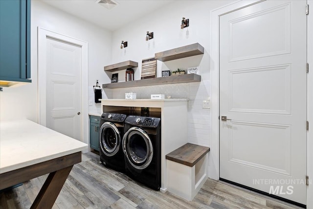 clothes washing area featuring cabinets, light hardwood / wood-style floors, and washer and dryer