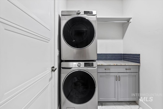 washroom featuring cabinets and stacked washer and clothes dryer