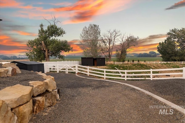 yard at dusk featuring a rural view and an outbuilding