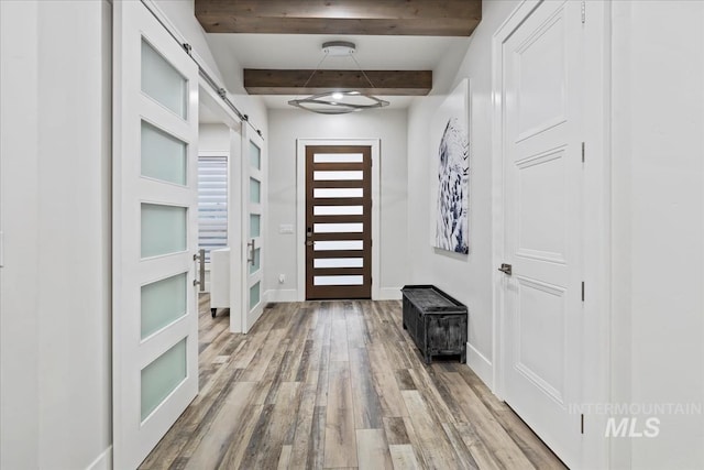 entrance foyer featuring hardwood / wood-style flooring, a barn door, and beam ceiling