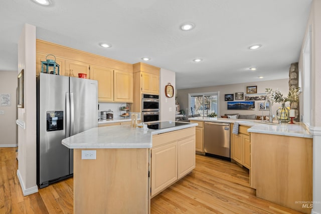 kitchen with kitchen peninsula, a center island, light hardwood / wood-style floors, and appliances with stainless steel finishes