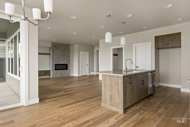 7017 S Zenith Ave, Meridian, ID 83642 - kitchen featuring a notable chandelier, an island with sink, light countertops, light wood finished floors, and a sink