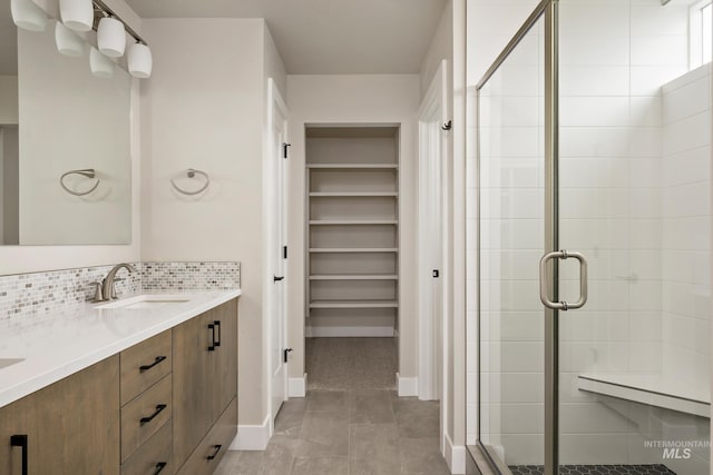 7017 S Zenith Ave, Meridian, ID 83642 - bathroom featuring double vanity, a stall shower, a spacious closet, backsplash, and a sink