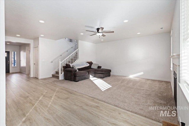 unfurnished living room with light colored carpet and ceiling fan