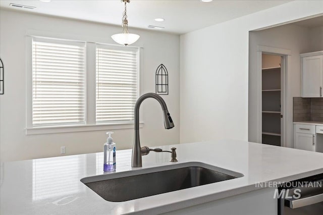 kitchen with pendant lighting, sink, decorative backsplash, and white cabinets