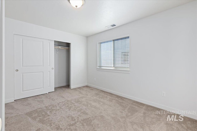 unfurnished bedroom with light carpet and a closet