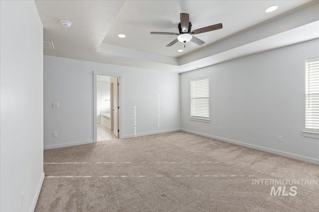 spare room with light carpet, a raised ceiling, and ceiling fan