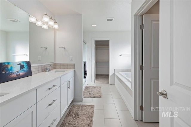 bathroom with tile patterned flooring, vanity, and a relaxing tiled tub