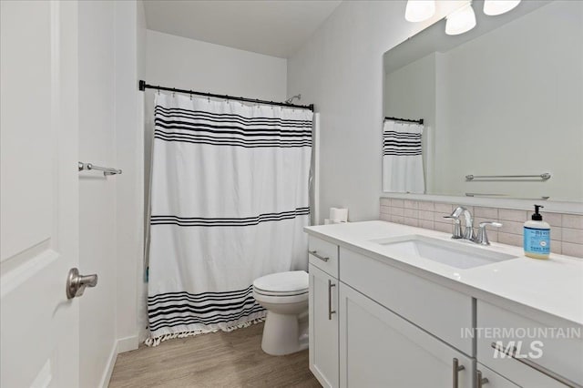 bathroom featuring tasteful backsplash, vanity, wood-type flooring, and toilet