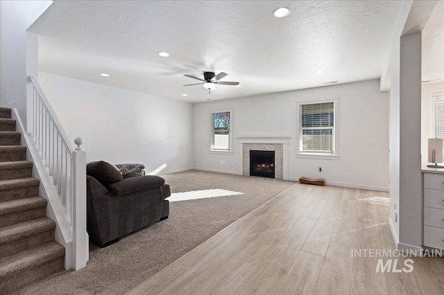 living room with ceiling fan, light hardwood / wood-style floors, and a textured ceiling