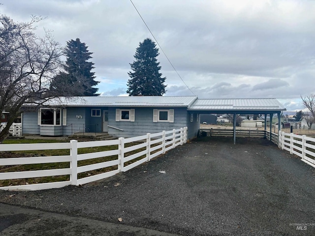 view of front of house featuring a fenced front yard, metal roof, a carport, and aphalt driveway