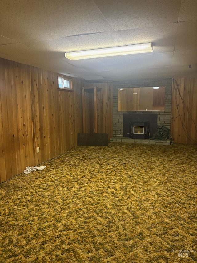 basement with a textured ceiling, wood walls, and carpet