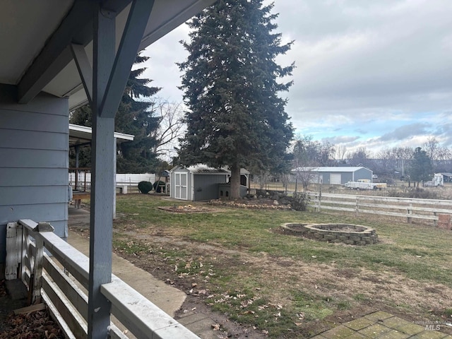 view of yard with a storage shed, an outdoor fire pit, fence, and an outbuilding