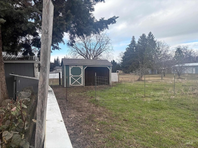 view of yard featuring an outbuilding, fence, and a storage shed