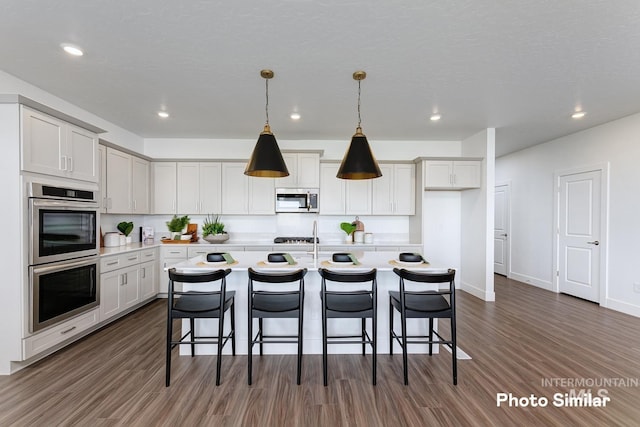 kitchen featuring light countertops, dark wood finished floors, a breakfast bar, and stainless steel appliances