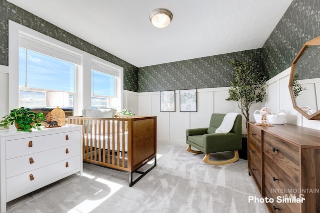 bedroom with carpet floors, a wainscoted wall, a decorative wall, and wallpapered walls