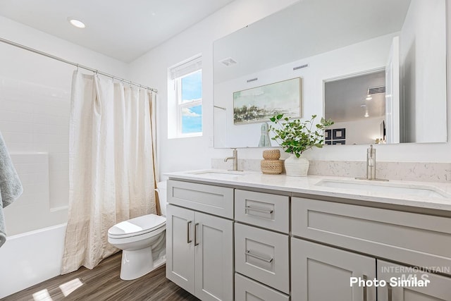 full bathroom with toilet, shower / bath combo with shower curtain, a sink, and wood finished floors