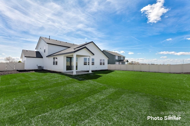 rear view of house with a lawn, a fenced backyard, a shingled roof, and a patio