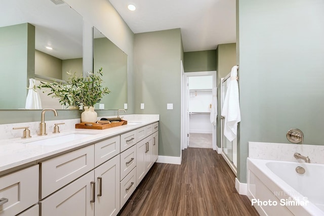 full bathroom featuring double vanity, a sink, a garden tub, and wood finished floors