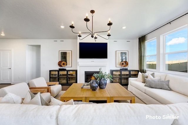 living area featuring an inviting chandelier, a glass covered fireplace, and recessed lighting