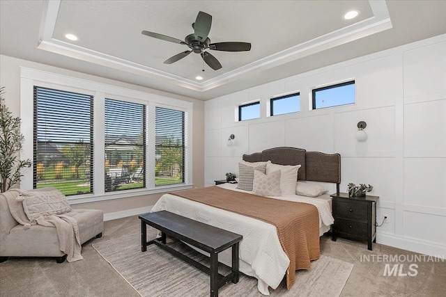 bedroom featuring a tray ceiling, light colored carpet, and a decorative wall