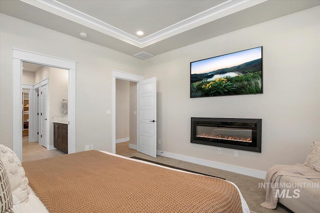 bedroom featuring baseboards, a raised ceiling, light colored carpet, a glass covered fireplace, and recessed lighting