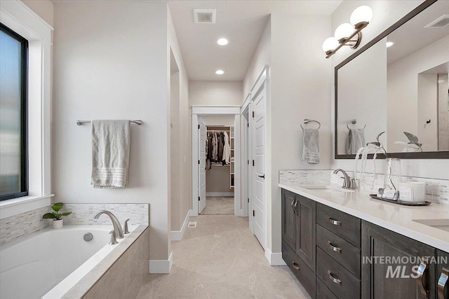 full bathroom with double vanity, a spacious closet, visible vents, and a sink