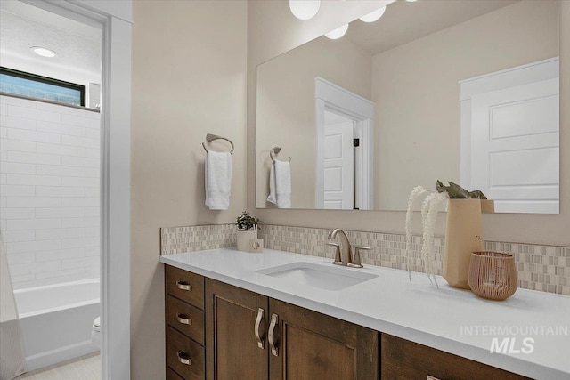 bathroom with toilet, backsplash, and vanity