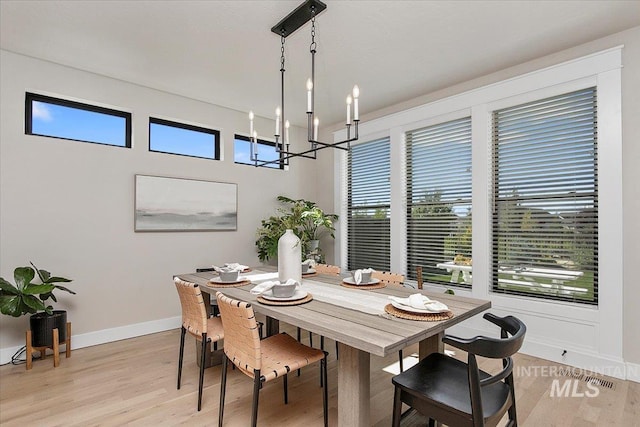 dining room with a notable chandelier, light wood-style flooring, and baseboards