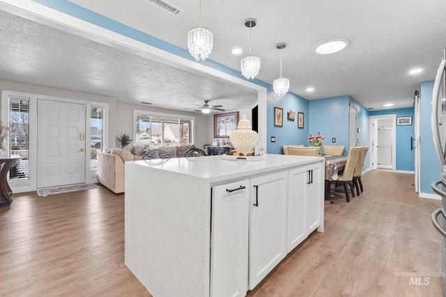 15201 Christopher, Caldwell, ID 83607 - kitchen featuring light wood-style floors, a center island, white cabinetry, hanging light fixtures, and open floor plan
