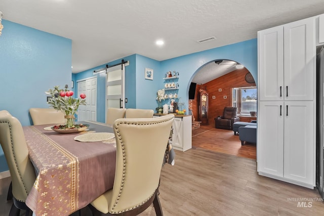 15201 Christopher, Caldwell, ID 83607 - dining room with arched walkways, wood walls, a barn door, light wood-style floors, and recessed lighting