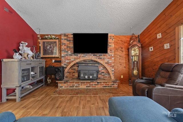 15201 Christopher, Caldwell, ID 83607 - living room featuring a wood stove, a textured ceiling, vaulted ceiling, wood finished floors, and wood walls