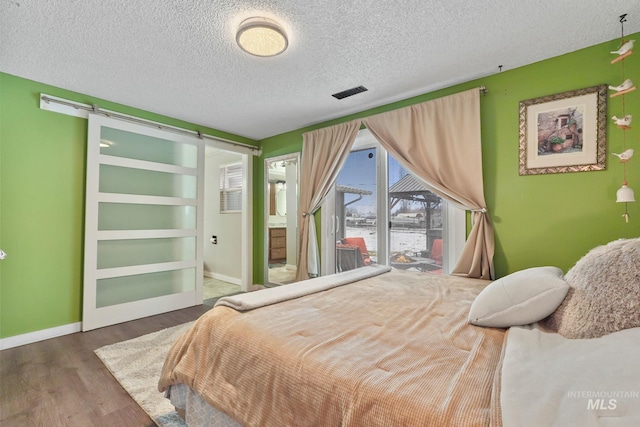 15201 Christopher, Caldwell, ID 83607 - bedroom featuring a barn door, a textured ceiling, wood finished floors, baseboards, and a water view