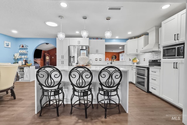 15201 Christopher, Caldwell, ID 83607 - kitchen featuring appliances with stainless steel finishes, premium range hood, arched walkways, a breakfast bar area, and tasteful backsplash