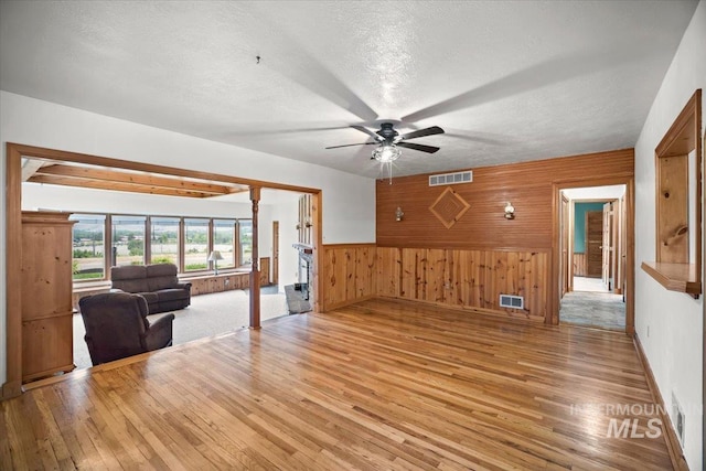 4523 N Mountain View Dr, Boise, ID 83704 - unfurnished living room with light wood finished floors, wood walls, ceiling fan, a textured ceiling, and wainscoting