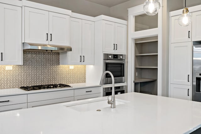 6257 N Vicenza Ln, Meridian, ID 83646 - kitchen with decorative backsplash, stainless steel appliances, sink, white cabinets, and hanging light fixtures