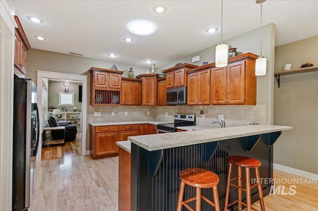 3524 Catalina Ave, Caldwell, ID 83605 - kitchen with stainless steel appliances, a peninsula, light wood-type flooring, light countertops, and brown cabinets