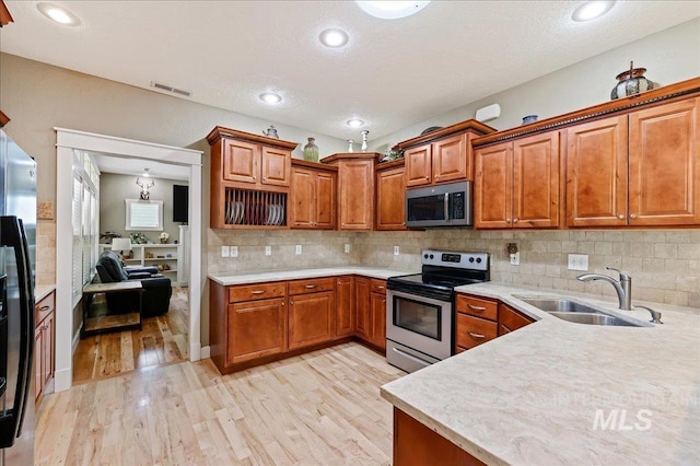 3524 Catalina Ave, Caldwell, ID 83605 - kitchen featuring appliances with stainless steel finishes, light wood-style floors, a sink, brown cabinetry, and light countertops