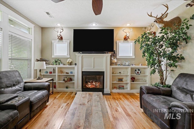 3524 Catalina Ave, Caldwell, ID 83605 - living room with hardwood / wood-style flooring, a textured ceiling, a glass covered fireplace, ceiling fan, and recessed lighting