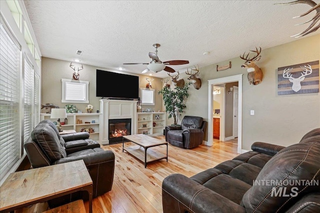 3524 Catalina Ave, Caldwell, ID 83605 - living area featuring a textured ceiling, ceiling fan, light wood-style floors, and a glass covered fireplace
