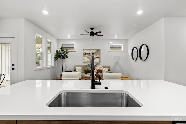 kitchen featuring recessed lighting, open floor plan, light countertops, and a sink